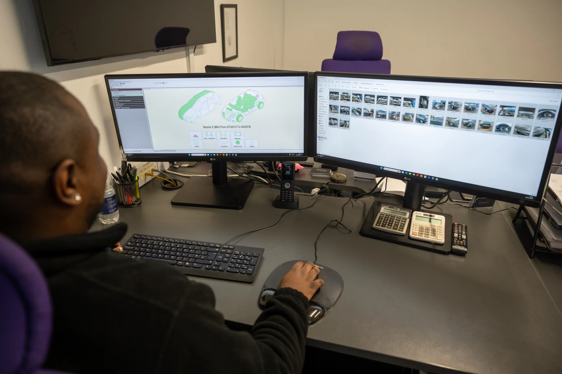 Technician reviewing a 3D vehicle damage model and repair photos on dual monitors using Audatex estimating software