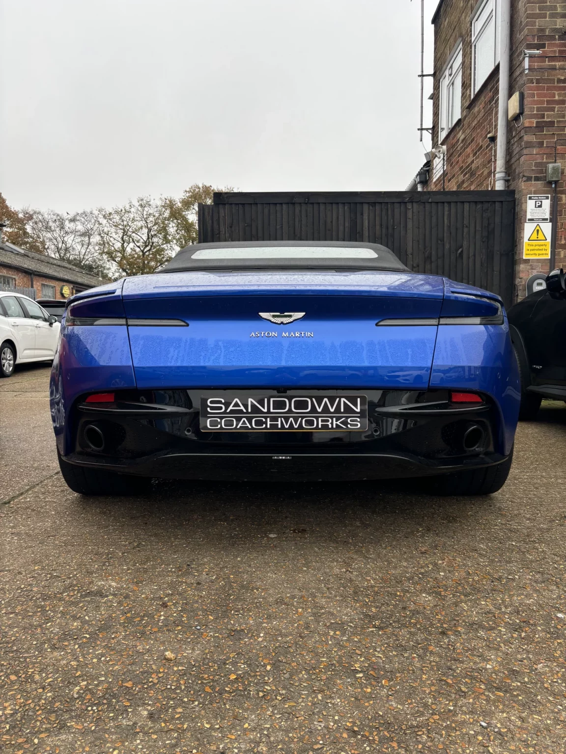 Rear view of a blue Aston Martin DB11 Volante with a Sandown Coachworks plate, highlighting expert bodywork services for Surrey and Berkshire.