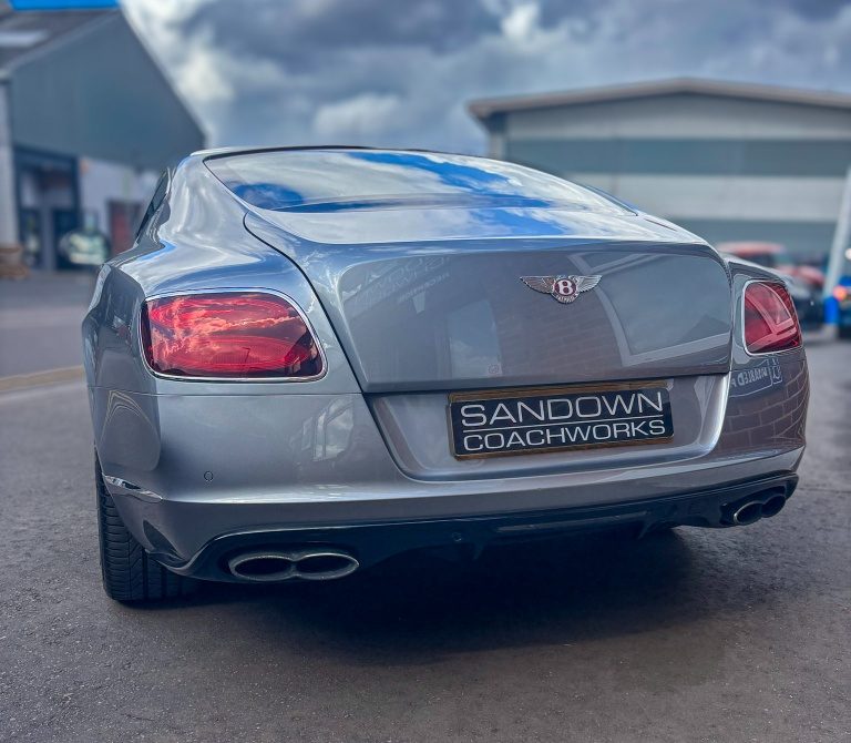 Rear view of a silver Bentley Continental GT featuring a Sandown Coachworks plate, demonstrating immaculate, cloud-reflecting rear bumper clearcoat restoration.