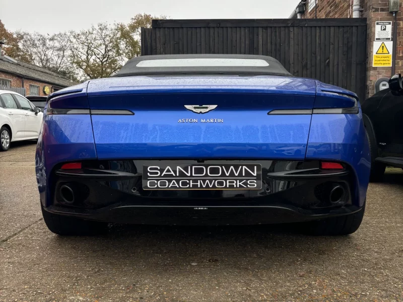 Rear view of a blue Aston Martin DB11 Volante with a Sandown Coachworks plate, highlighting expert bodywork services for Surrey and Berkshire.