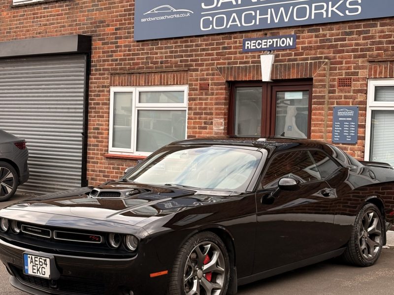 Prestige black Dodge Challenger parked outside Sandown Coachworks reception, showcasing pristine factory-level paint finish.