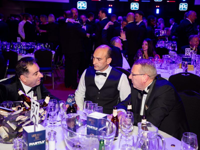 The Sandown Coachworks team networking and discussing industry innovations during the ABP awards dinner in a formal event setting.