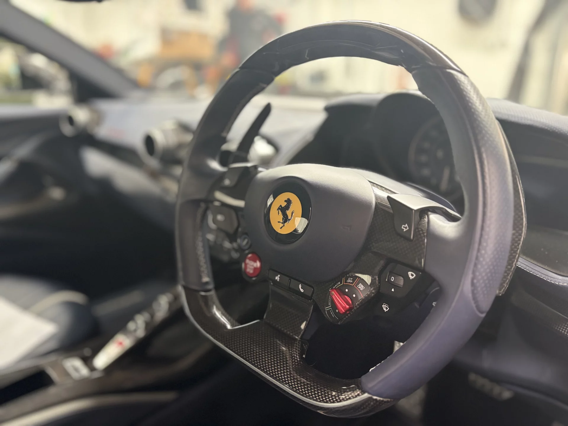Detailed view of a Ferrari carbon fiber steering wheel and interior dashboard, showcasing the precision care provided by our specialist team.