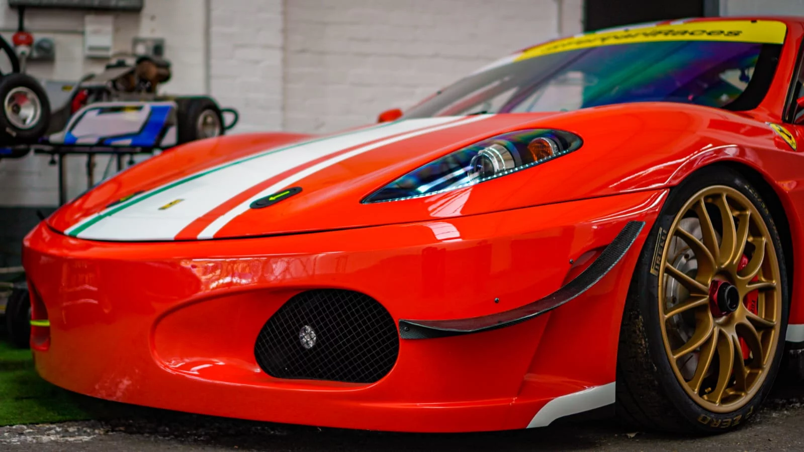 Close-up of the pristine red paint and carbon fiber detailing on a Ferrari race car at Sandown Coachworks prestige bodyshop.