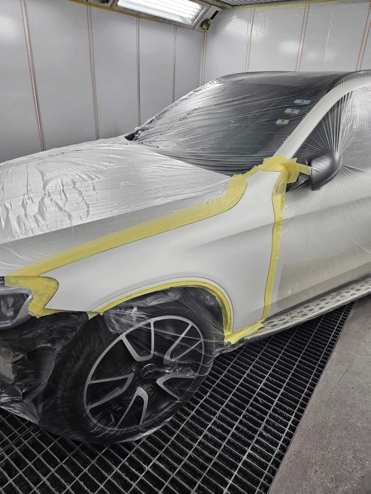 A silver Mercedes-Benz undergoing professional masking and preparation at Sandown Coachworks Shepperton before moving to the paint booth for bodywork repairs.