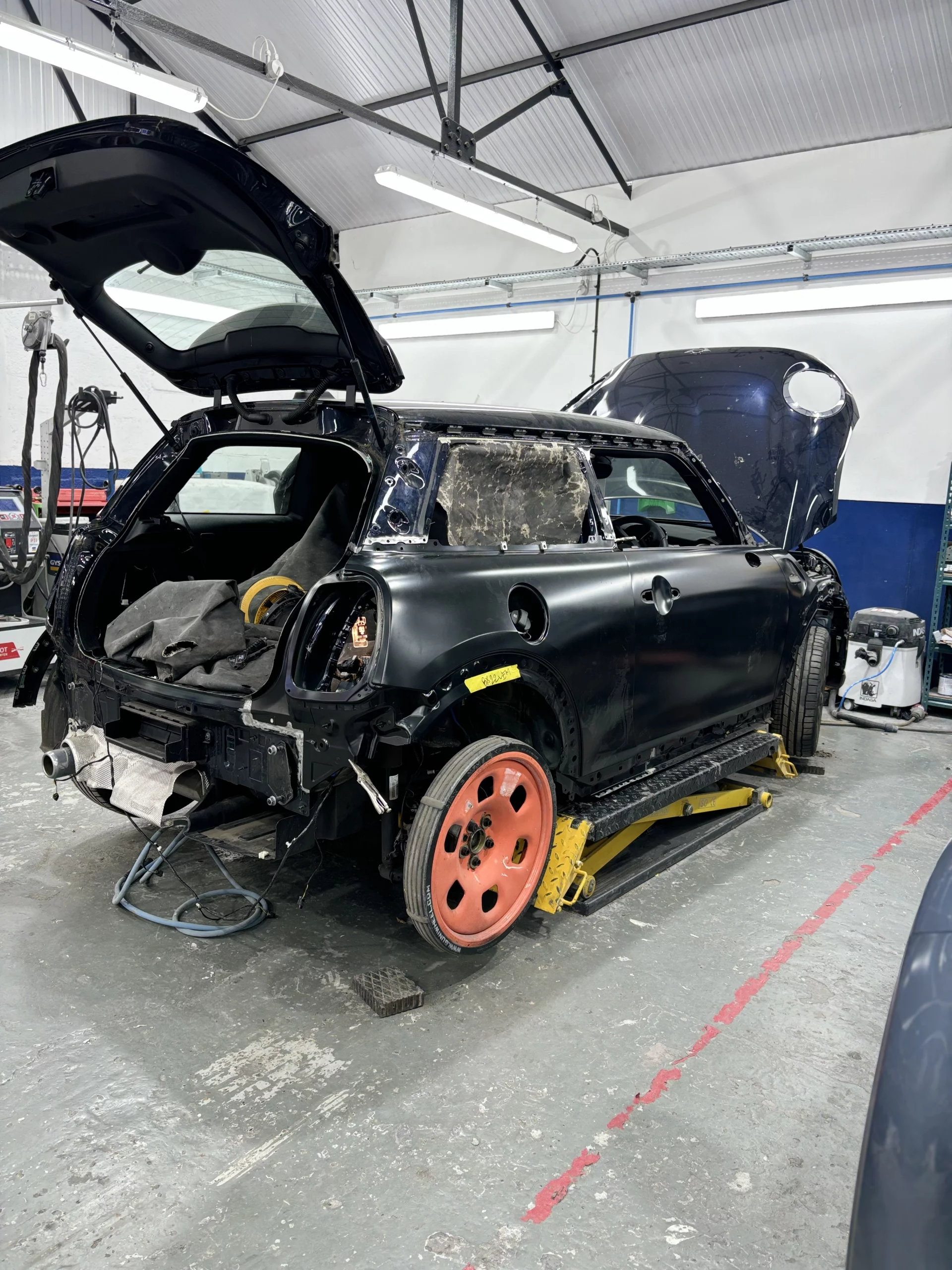 A new OEM replacement rear quarter panel being precision-fitted and aligned to a Mini Cooper in the Sandown Coachworks workshop.