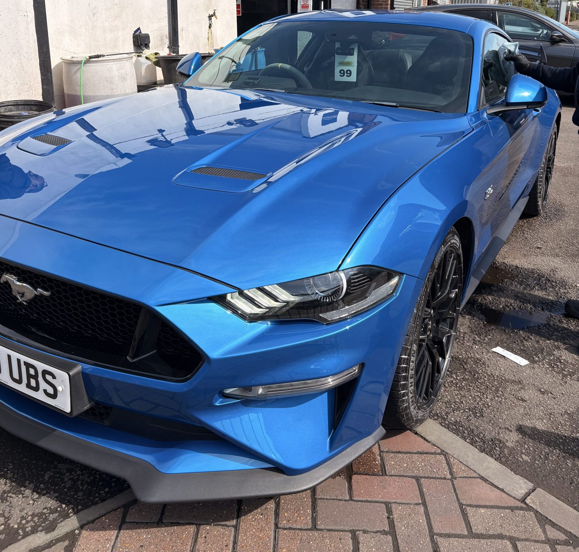 BSI-certified technician performing precision paintwork on a high-performance blue Ford Mustang at Sandown Coachworks.