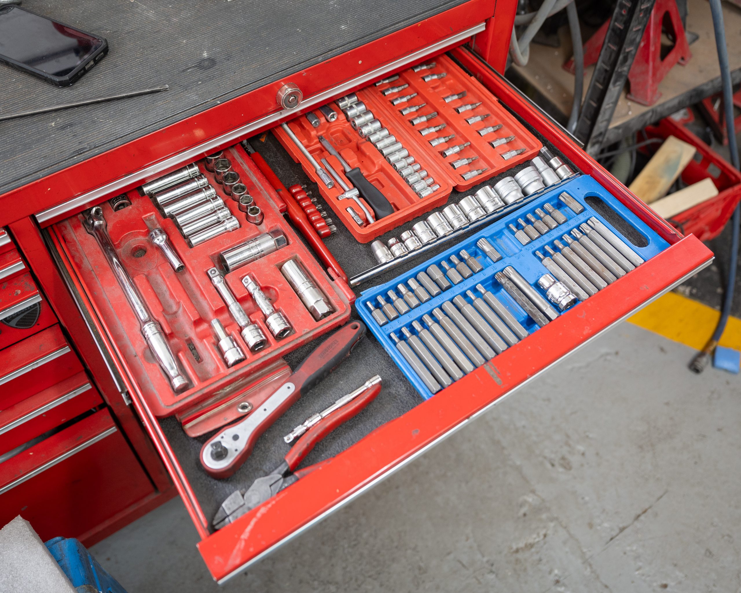A neatly organized professional mechanic's tool drawer featuring various socket sets and wrenches for precision vehicle repair.