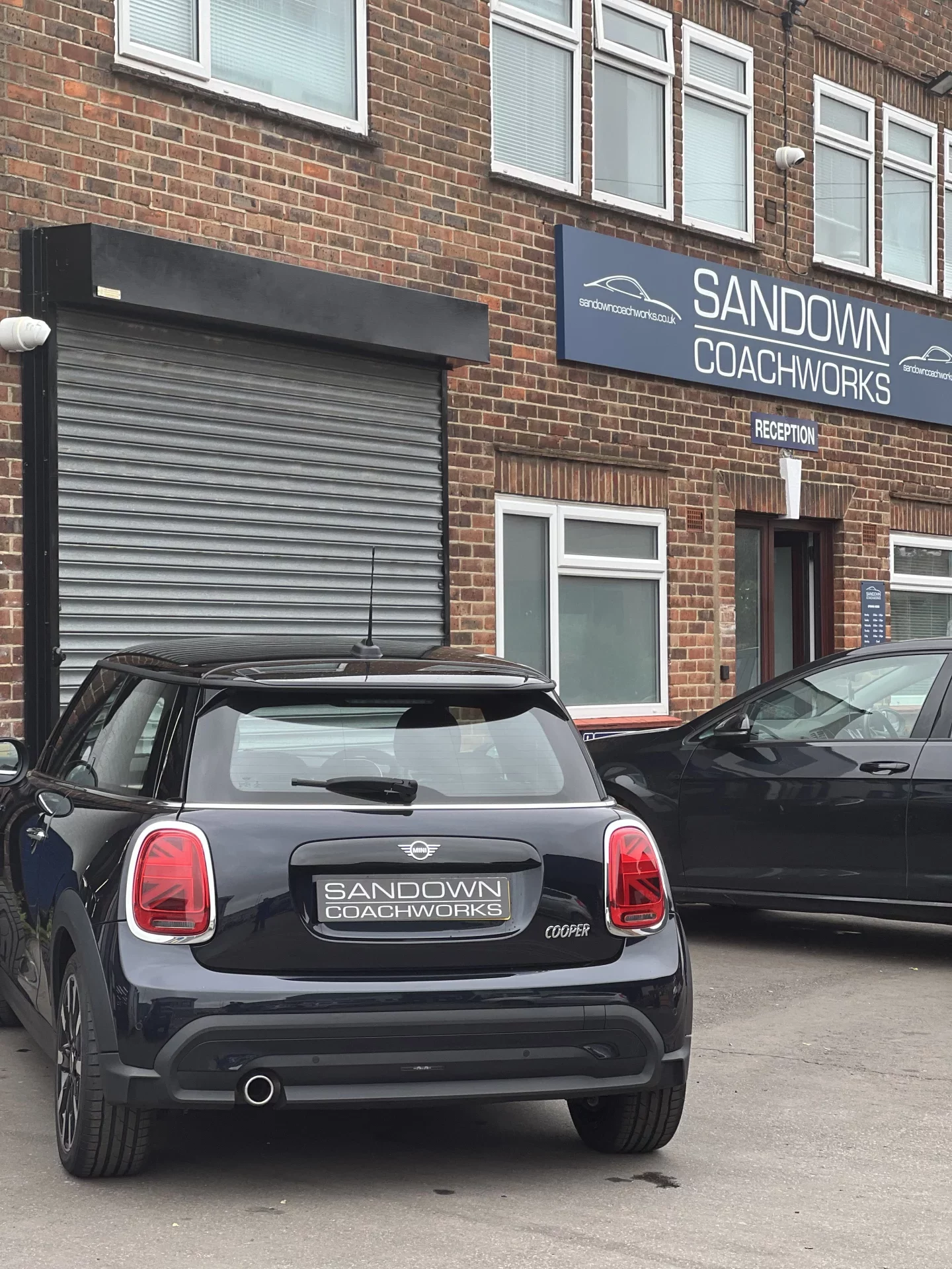 A fully restored and valeted black Mini Cooper parked outside the Sandown Coachworks workshop after a professional accident repair