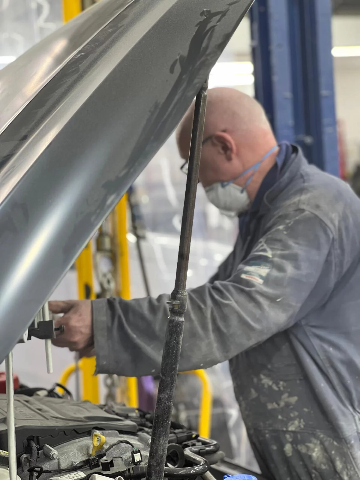 Professional technician at Sandown Coachworks performing precision engine bay and bodywork repairs while wearing protective safety gear.